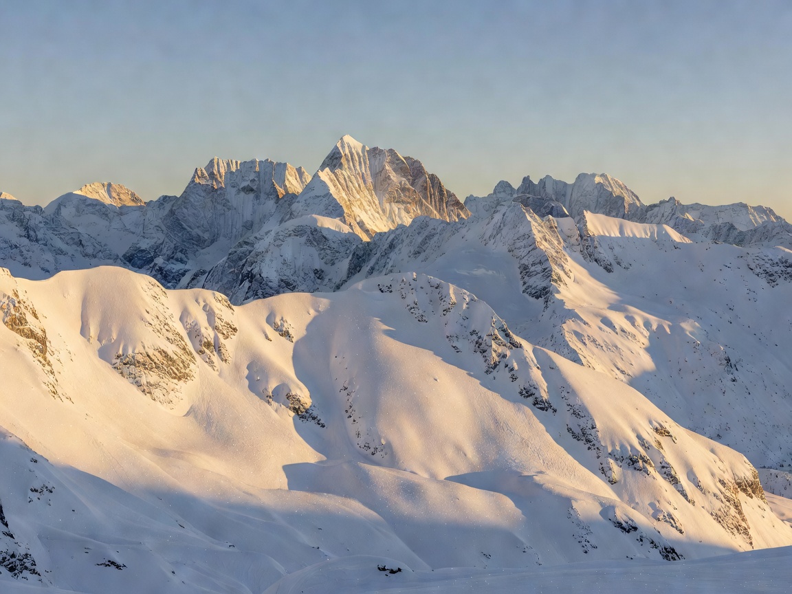 Scenic snow covered Alpine mountain peaks under clear morning sky